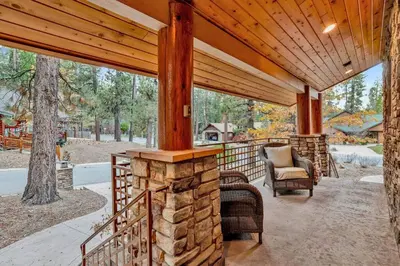 an outdoor patio with a wooden roof and a stone fireplace at The Spa at Winterset- Incredible Resort Estate Chalet- Indoor Hot Tub- Games in Big Bear Lake