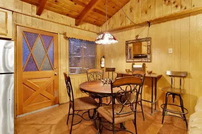 a dining room with a table and chairs and a refrigerator at Pine Cone Cottage by Big Bear Vacations Adorable Walk To Lake Furnished Chalet in Big Bear Lake