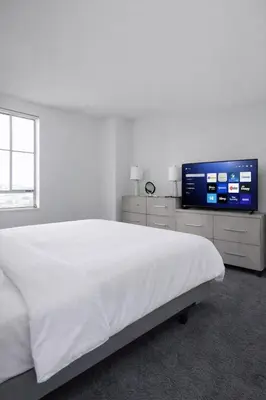 a white bedroom with a large bed and a flat screen tv at Spacious 2 Bedroom 2 Bathroom Unit Great Location in Los Angeles