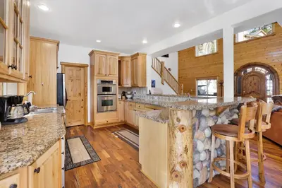 a kitchen with wooden cabinets and a stone counter top at Cozy Lakeview Hideaway by Big Bear Vacations Amazing Fawnskin Log Cabin Chalet in Fawnskin