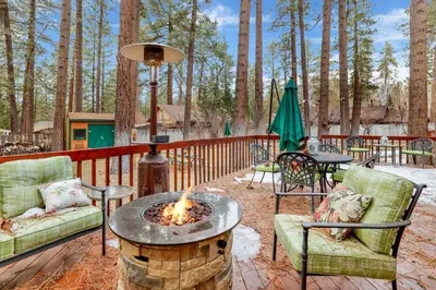 a fire pit on a deck with chairs and tables at Fawnskin Log Cabin- Luxurious Group Log Cabin Estate- Hot Tub- Walk to Lake in Fawnskin