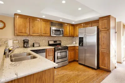 a kitchen with wooden cabinets and stainless steel appliances at Forest Shores Lake View Condo by Big Bear Vacations Lakefront Village in Big Bear Lake