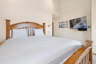 a bedroom with a large white bed and a tv at Forest Shores Lake View Condo by Big Bear Vacations Lakefront Village in Big Bear Lake