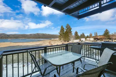 a balcony with a table and chairs and a view of a beach at Forest Shores Lake View Condo by Big Bear Vacations Lakefront Village in Big Bear Lake