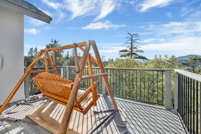 a wooden swing sitting on a deck on a balcony at Sunset Ridge Villa- Incredible Log Cabin Estate- Hot Tub- Game Tables- in Big Bear Lake