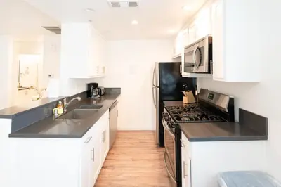 a kitchen with white cabinets and a black stove top oven at Modern Furnished 1-Bedroom with Free Parking in Koreatown close to DT LA in Los Angeles