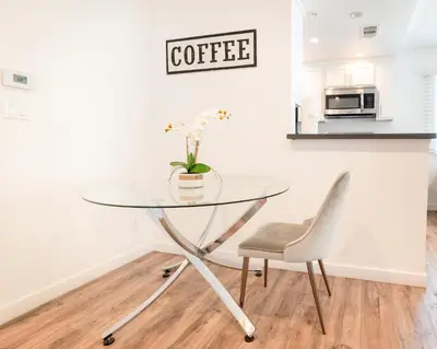 a glass table with a chair and a coffee sign on a wall at Modern Furnished 1-Bedroom with Free Parking in Koreatown close to DT LA in Los Angeles