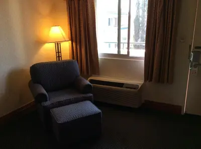 a room with a chair and a lamp and a window at New Century Inn in San Gabriel
