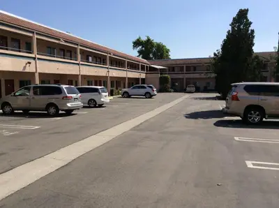 a parking lot with cars parked in front of a building at New Century Inn in San Gabriel