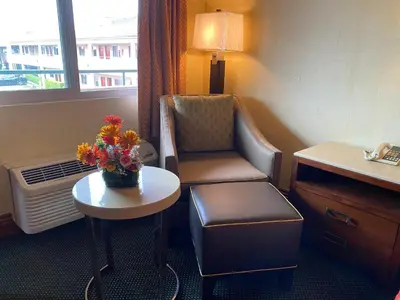 a hotel room with a chair and a table with flowers at New Century Inn in San Gabriel