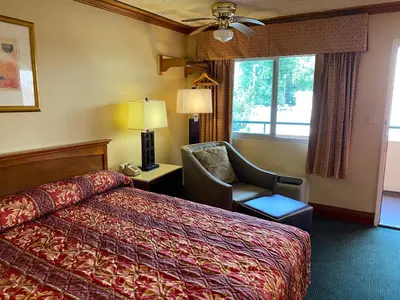 a hotel room with a bed and a chair and a window at New Century Inn in San Gabriel
