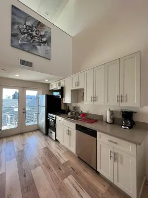 a kitchen with white cabinets and a wooden floor at Modern One-Bed Loft in Hollywood Sign View & Free Parking in Los Angeles