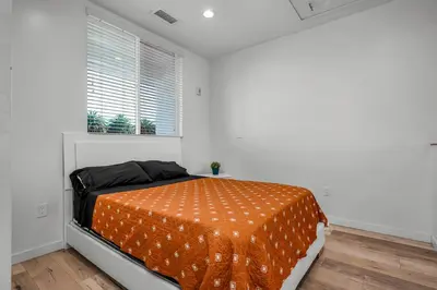 a bedroom with a bed with an orange comforter at New 1 Bedroom Loft with View of Hollywood Sign in Los Angeles
