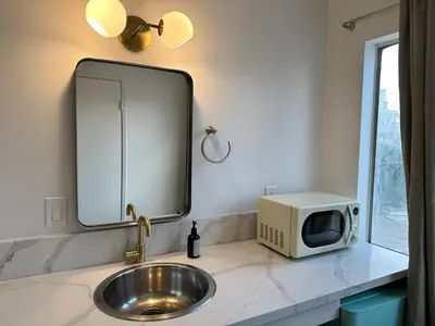 a bathroom sink with a mirror and a microwave at Sierra Motor Lodge - A Sierra Blue Hotel in Mojave