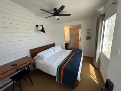 a bedroom with a bed and a desk and a ceiling fan at Sierra Motor Lodge - A Sierra Blue Hotel in Mojave