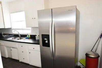 a stainless steel refrigerator in a kitchen with white cabinets at Hollywood Business Apartments in Los Angeles