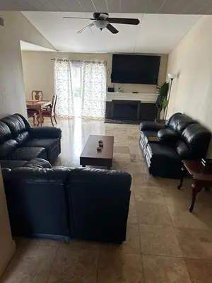 a living room with black leather couches and a table at Buxton Private Room and Bath Wheel Chair Access in Rialto