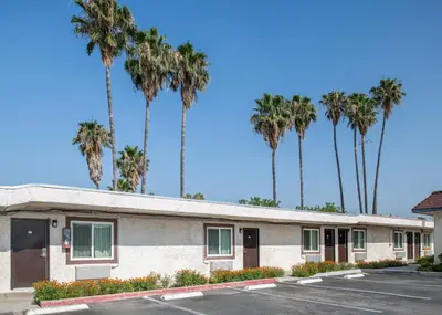 a building with palm trees in the background at Starlite Motel in San Bernardino
