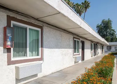 a white building with a window and a sidewalk at Starlite Motel in San Bernardino