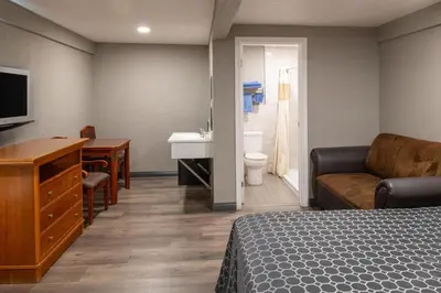 a hotel room with a bed and a desk and a sink at Starlite Motel in San Bernardino