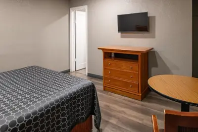 a bedroom with a bed and a dresser with a tv at Starlite Motel in San Bernardino