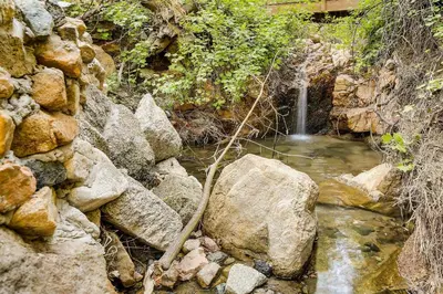 a stream of water with rocks and a waterfall at Peaceful Pines Running Springs Home with 3 Decks in Running Springs
