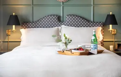 a white bed with a bottle of wine and flowers on it at Villa Carlotta - 30 Day Requirement in Los Angeles