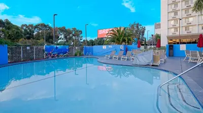 a large swimming pool with chairs and a building at Suites Los Angeles CA Los Angeles LAX in Inglewood
