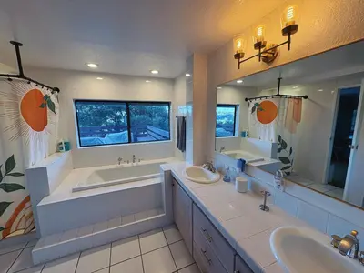 a bathroom with two sinks and a tub and two mirrors at Apartment with Private Deck & Mountain Views in Topanga