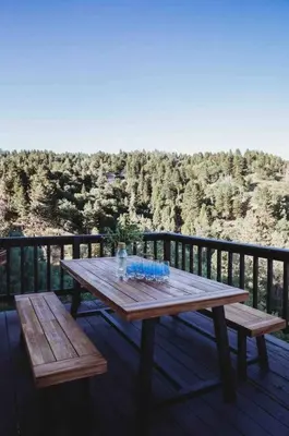 a wooden table on a deck with two benches at @wild_olive_den ~ Serene Weekend Getaway Cabin in Running Springs