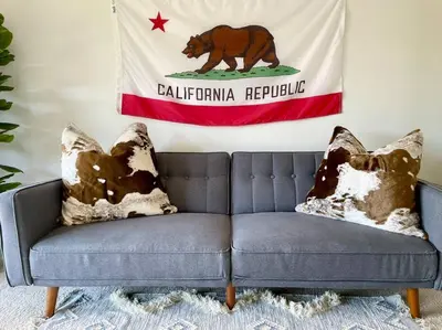 a flag of a bear on a wall with a couch at @wild_olive_den ~ Serene Weekend Getaway Cabin in Running Springs