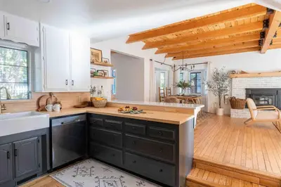 a kitchen with black cabinets and a wooden floor at Wild Olive Lodge ° Serene grandma chíc getaway cabin in Running Springs