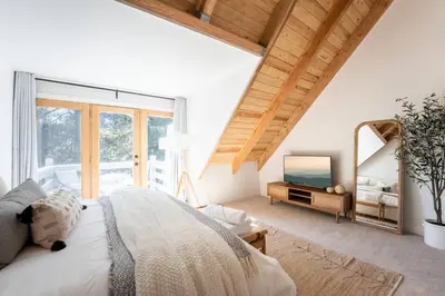 a bedroom with a large bed and a mirror at Wild Olive Lodge ° Serene grandma chíc getaway cabin in Running Springs