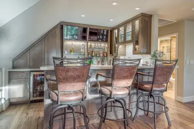 a kitchen with a bar with three bar stools at Lake Front Modern Luxury in Lake Arrowhead
