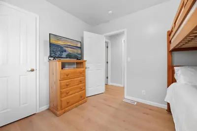 a bedroom with a bed and a wooden dresser at 3 Cubs Lakefront - Stunning lakeside home with Hot Tub, Foosball, and Lake View in Big Bear Lake