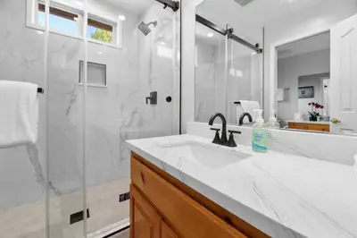 a white bathroom with a sink and a shower at 3 Cubs Lakefront - Stunning lakeside home with Hot Tub, Foosball, and Lake View in Big Bear Lake
