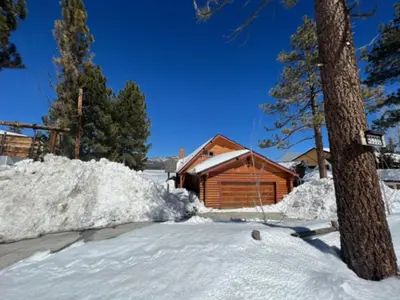 a cabin with a pile of snow in front of it at 3 Cubs Lakefront - Stunning lakeside home with Hot Tub, Foosball, and Lake View in Big Bear Lake