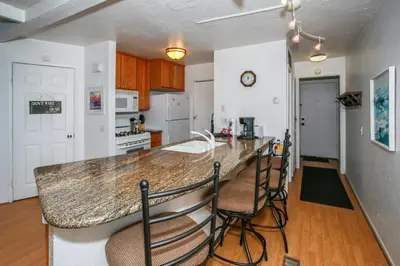 a kitchen with a counter and some chairs in it at Bayview Condo - Condo is cozy and a great location for kayaking and paddle boarding! in Big Bear Lake