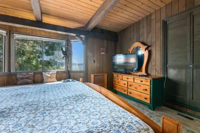 a bedroom with a bed and a flat screen tv at Alpine Lakefront - Lakefront cabin and all the amenities really fun from the pool table and spa in Big Bear Lake