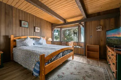 a bedroom with a bed and a flat screen tv at Alpine Lakefront - Lakefront cabin and all the amenities really fun from the pool table and spa in Big Bear Lake