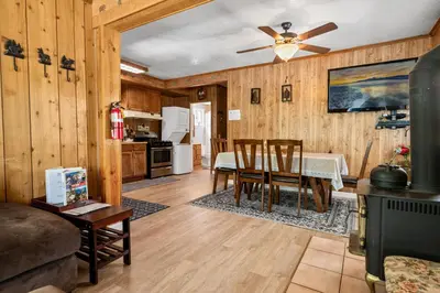 a living room with a dining room table and a ceiling fan at Apples Delight -WALK TO THE LAKE! Enjoy the huge backyard with lovely forest views ! in Big Bear Lake