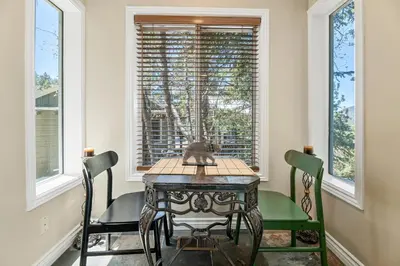 a dining room with a table and chairs and windows at BB Lake View Lodge - Gorgeous Lakeviews, Hot Tub, Jetted Tub, and Firepit! in Big Bear Lake