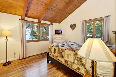 a bedroom with a bed and a lamp at Bear Claw Cabin - Perfect location with an amazing game room and hot tub! in Big Bear Lake