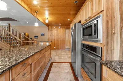 a kitchen with stainless steel appliances and wooden cabinets at Bear Family Cabin - Stay together & play together! Foosball, billiards, hot tub, walk to lake! in Big Bear Lake