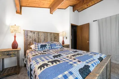 a bedroom with a bed with a blue and white comforter at Bear PAC Hideout - Walk to Alpine Slide and only minuetes to The Village! Billiards and foosball! in Big Bear Lake