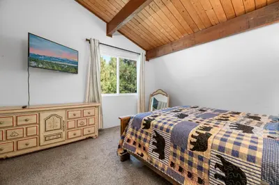 a bedroom with a bed and a tv on the wall at Bear PAC Hideout - Walk to Alpine Slide and only minuetes to The Village! Billiards and foosball! in Big Bear Lake