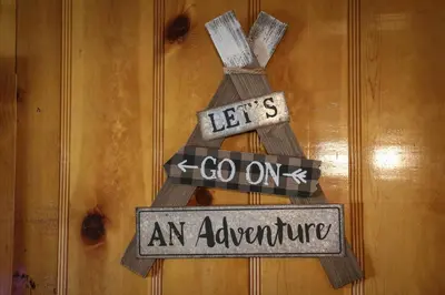 a wooden door sign that says lets go on an adventure at Bear Paw Cabin - Cozy and quaint, the perfect mountain getaway! in Big Bear Lake