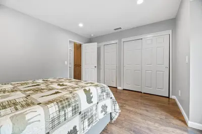 a bedroom with a bed and white walls and wooden floors at Bear Retreat - Modern location within walking distance to Snow Summit with a private hot tub! in Big Bear Lake