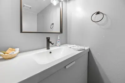 a white bathroom with a sink and a mirror at Bear Retreat - Modern location within walking distance to Snow Summit with a private hot tub! in Big Bear Lake