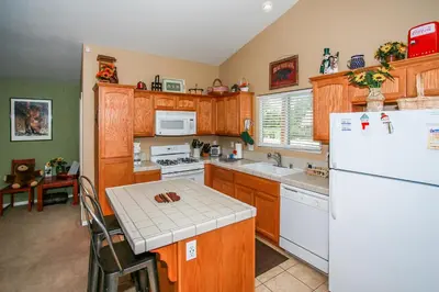 a kitchen with wooden cabinets and a white refrigerator at Ben's Cool Cabin - Phenomenal views and an ideal location close to all the local attractions! in Big Bear Lake